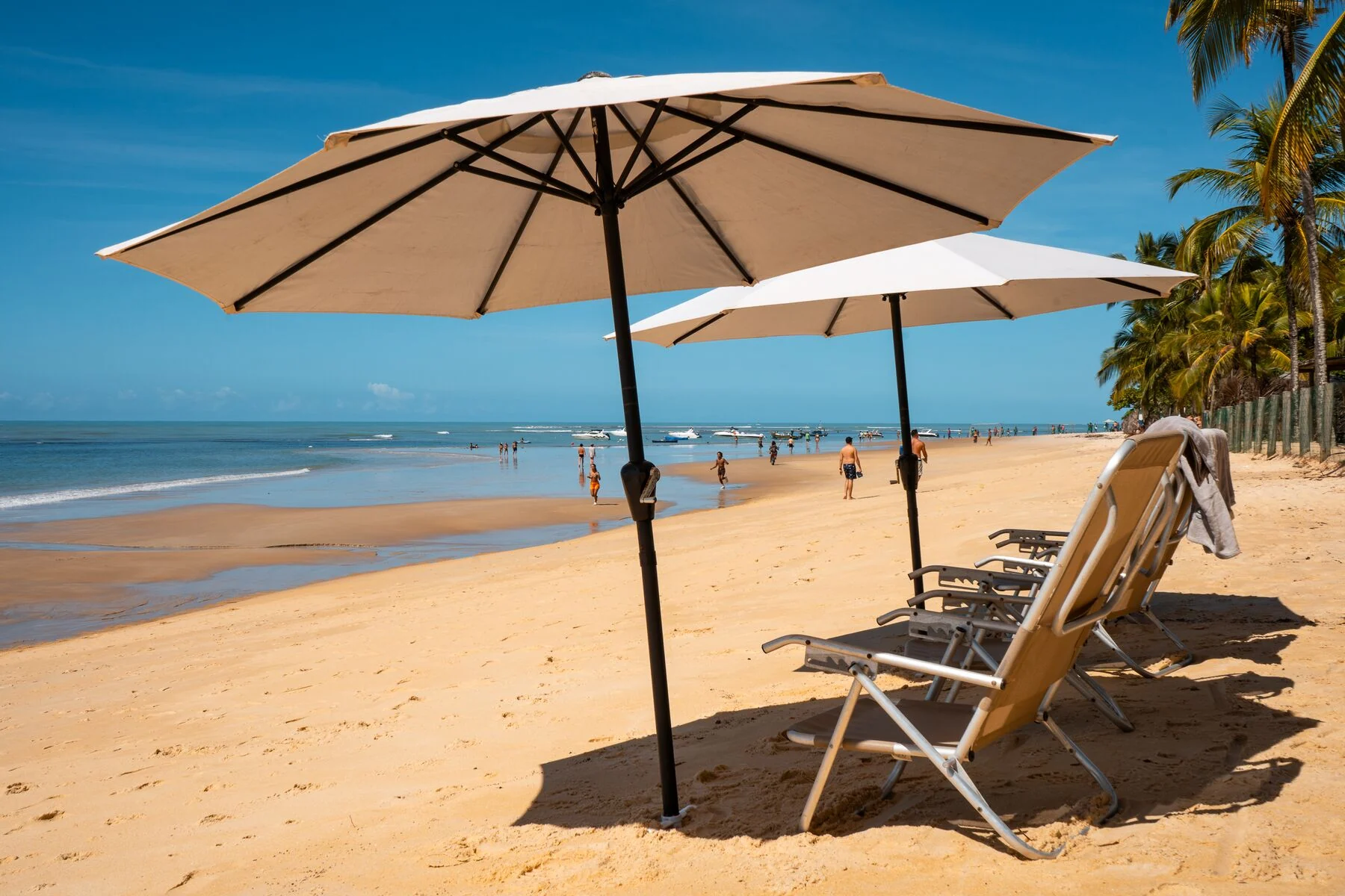 Apoio de praia com guarda-sóis claros e areia clara